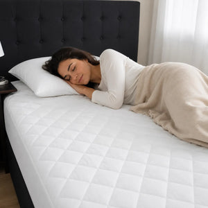 Mujer descansando sobre una cama con protector de colchón acolchado blanco y transpirable.