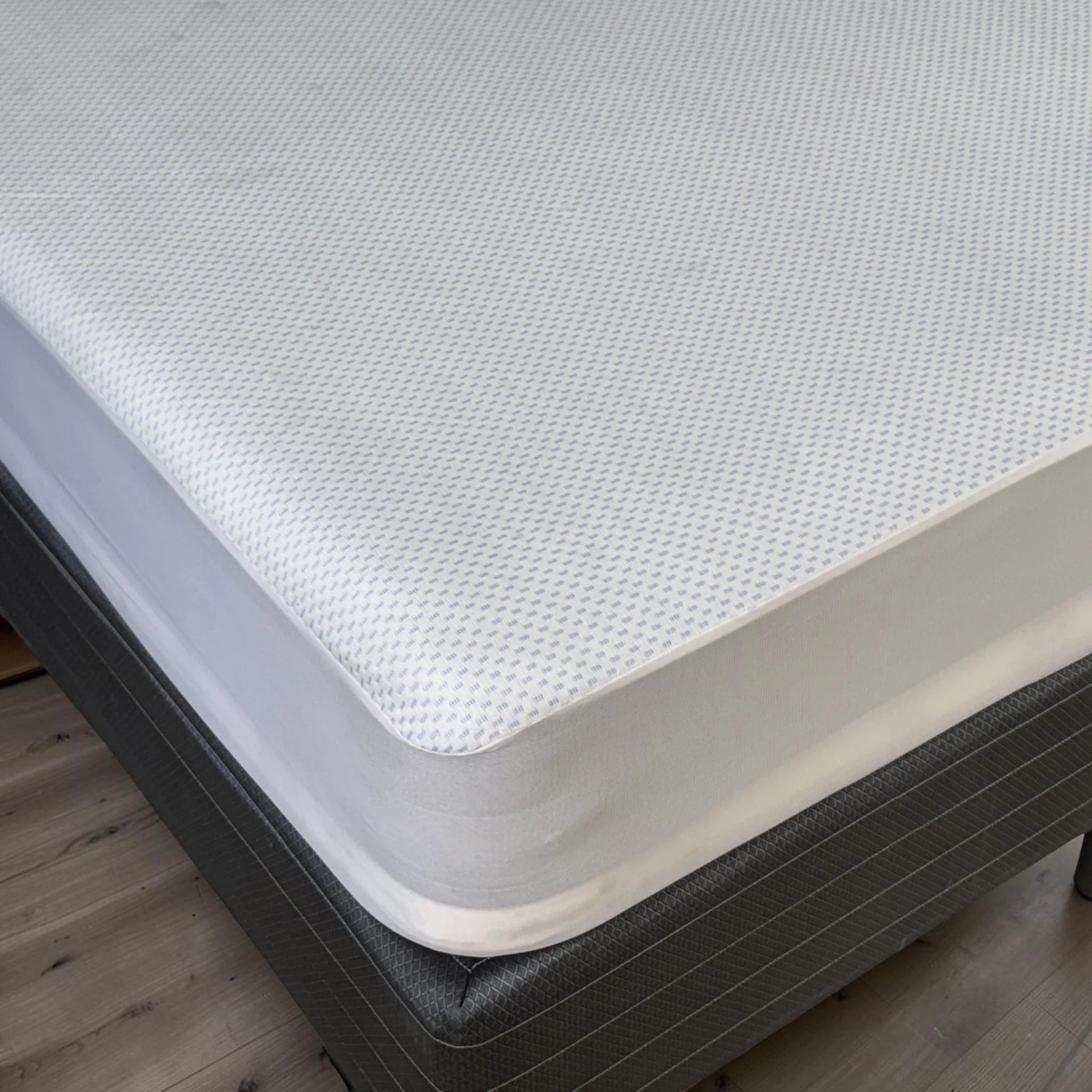 Detalle de la esquina del protector de colchón impermeable Cooling blanco instalado sobre un colchón Full con ajuste profundo y superficie transpirable de tacto fresco.