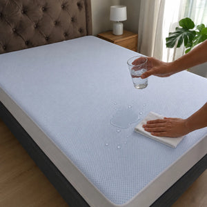 Protector de colchón impermeable Cooling demostrando protección contra líquidos mientras el agua permanece sobre la superficie y se limpia fácilmente con una toalla.