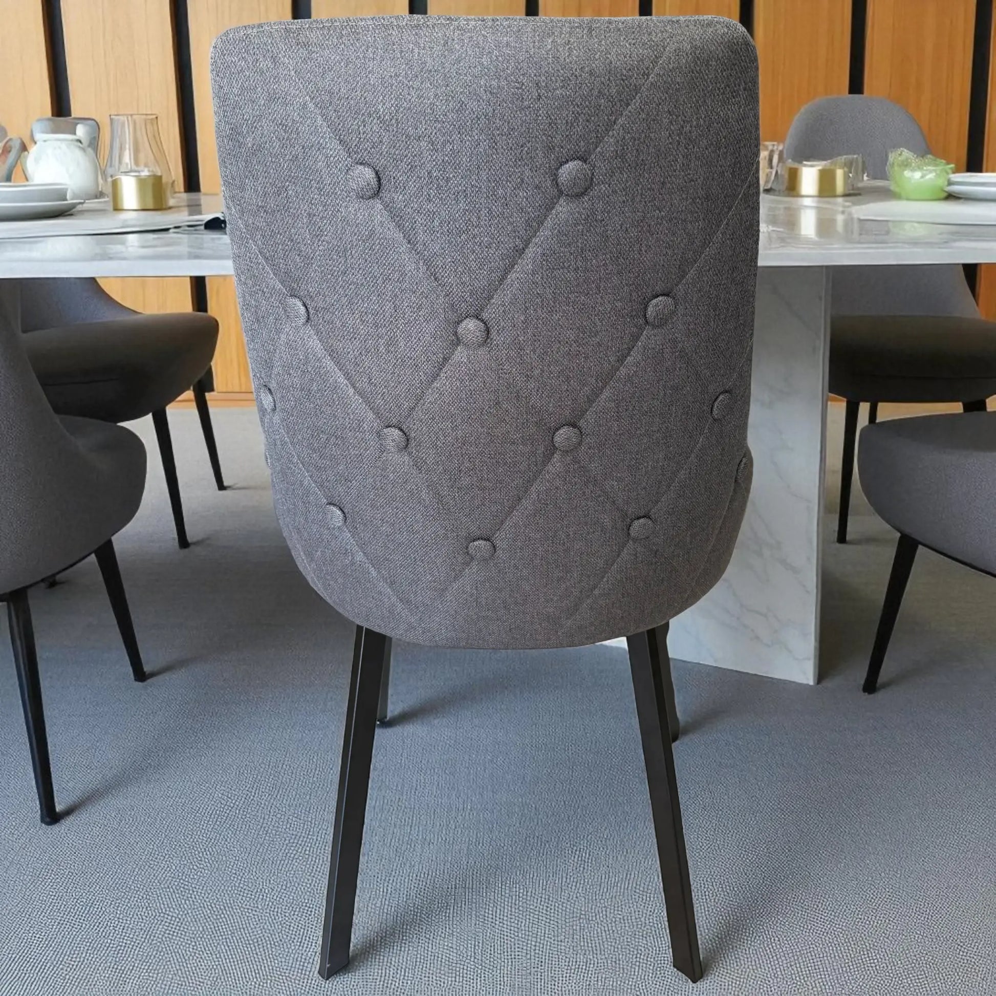 Detalle del respaldo capitonado en forma de diamante de la silla gris oscuro del comedor Ambienta DT-06-2237, con patas negras de metal.