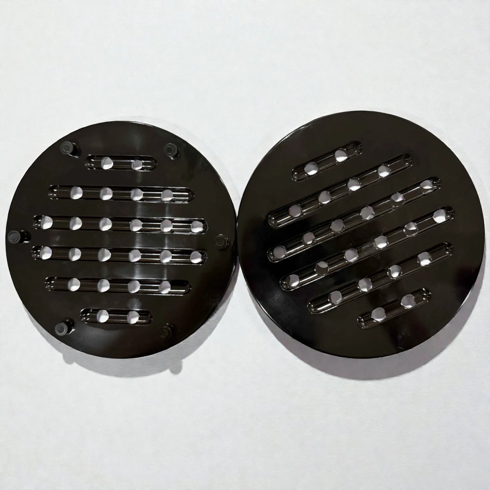 Par de salvamanteles redondos negros para ollas y sartenes, vistos desde arriba sobre fondo blanco.