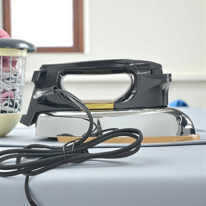 Vista lateral izquierda de la plancha Sankey JP-83, cuerpo cromado con mango negro, suela cerámica dorada y cable de alimentación largo sobre mesa de planchar.