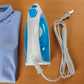 Plancha a vapor Sankey PV-108 azul vista desde arriba, con cable blanco enrollado y camisa doblada al lado.