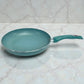Sartén individual del juego SANKEY color verde turquesa con recubrimiento antiadherente tipo marble coating; vista lateral sobre superficie tipo mármol con el mango hacia la derecha y el interior del sartén visible.