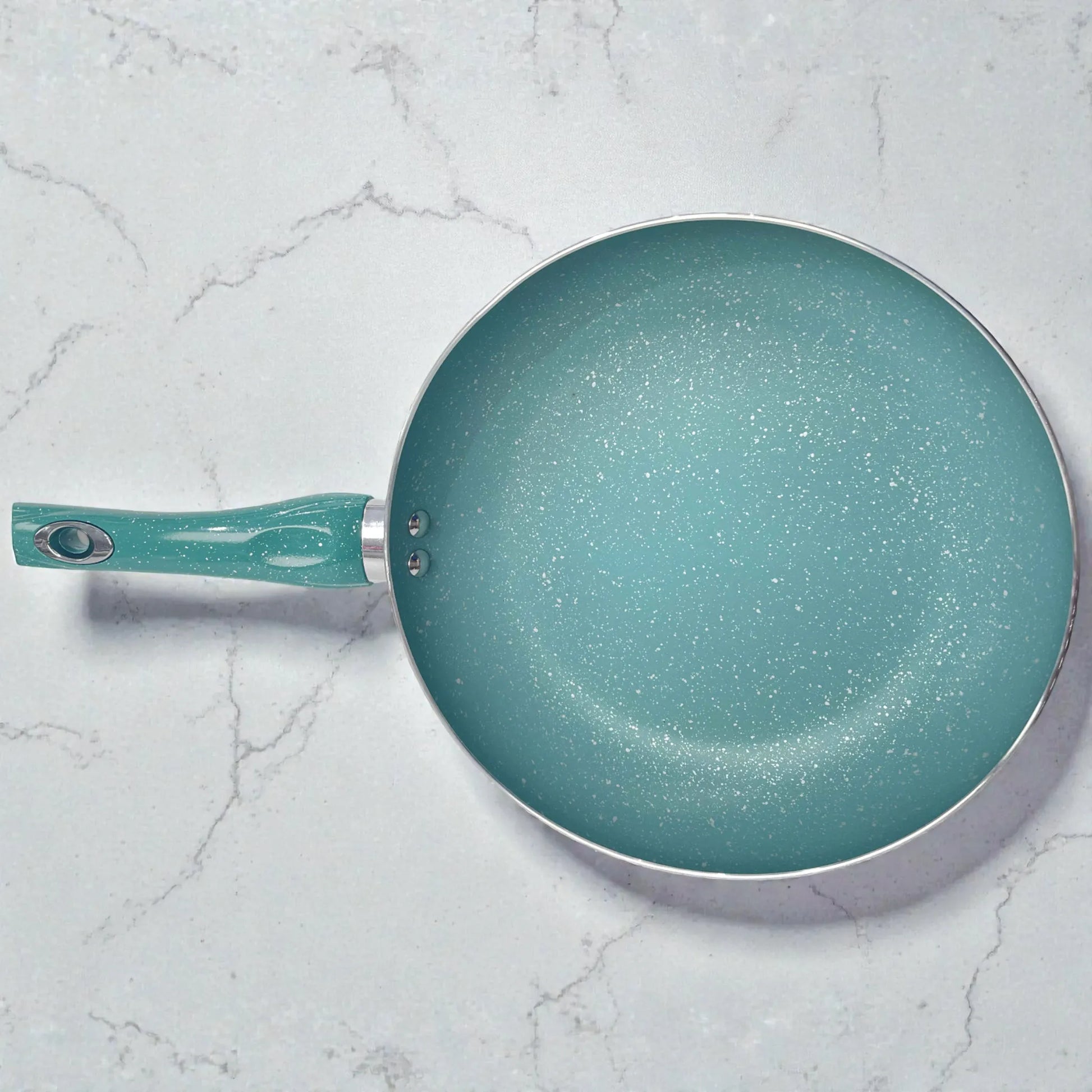 Vista superior de sartén SANKEY verde turquesa con recubrimiento antiadherente tipo marble coating (acabado granito); mango orientado a la izquierda y superficie interior moteada visible sobre fondo tipo mármol.