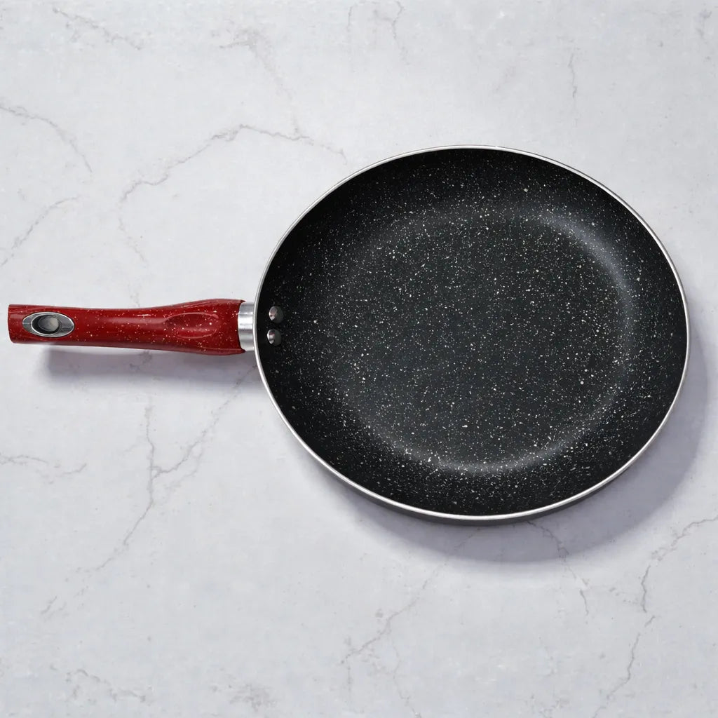 Vista superior de sartén SANKEY W1626BLG antiadherente con recubrimiento marble coating, interior negro moteado y mango rojo, sobre fondo tipo mármol con el mango orientado hacia la izquierda.