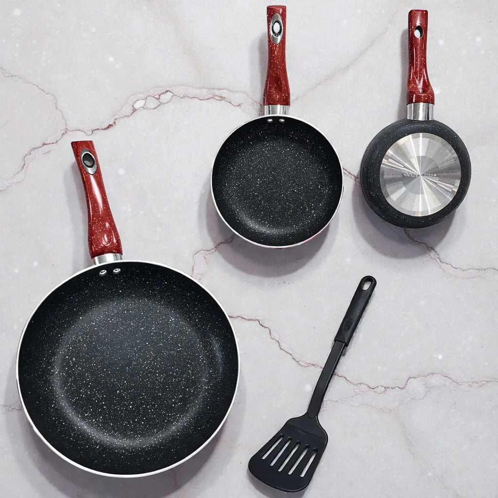Vista superior tipo flat lay del set de sartenes SANKEY W1626BLG de 3 piezas (16/20/26 cm) en fondo mármol; interior negro con textura tipo piedra y mango rojo, con una sartén volteada mostrando la base metálica circular y una espátula negra decorativa.