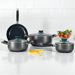 Set Sankey W-757 color gris granito; sartén 24 cm de pie al fondo, olla 24 cm con tapa al centro, olla 18 cm izquierda, cacerola 16 cm derecha; pelador cerámico amarillo al frente.