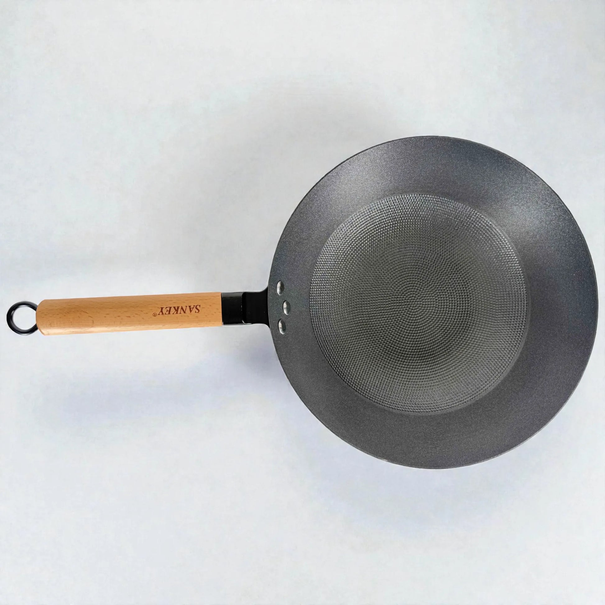 Wok Sankey negro de hierro fundido 30 cm (12”), flat lay horizontal sobre fondo blanco, con mango de madera e interior tipo panal.