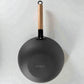 Vista inferior del wok Sankey de hierro fundido negro 30 cm (12 pulgadas), mostrando base exterior con logo Sankey y mango de madera con aro para colgar, sobre fondo blanco.