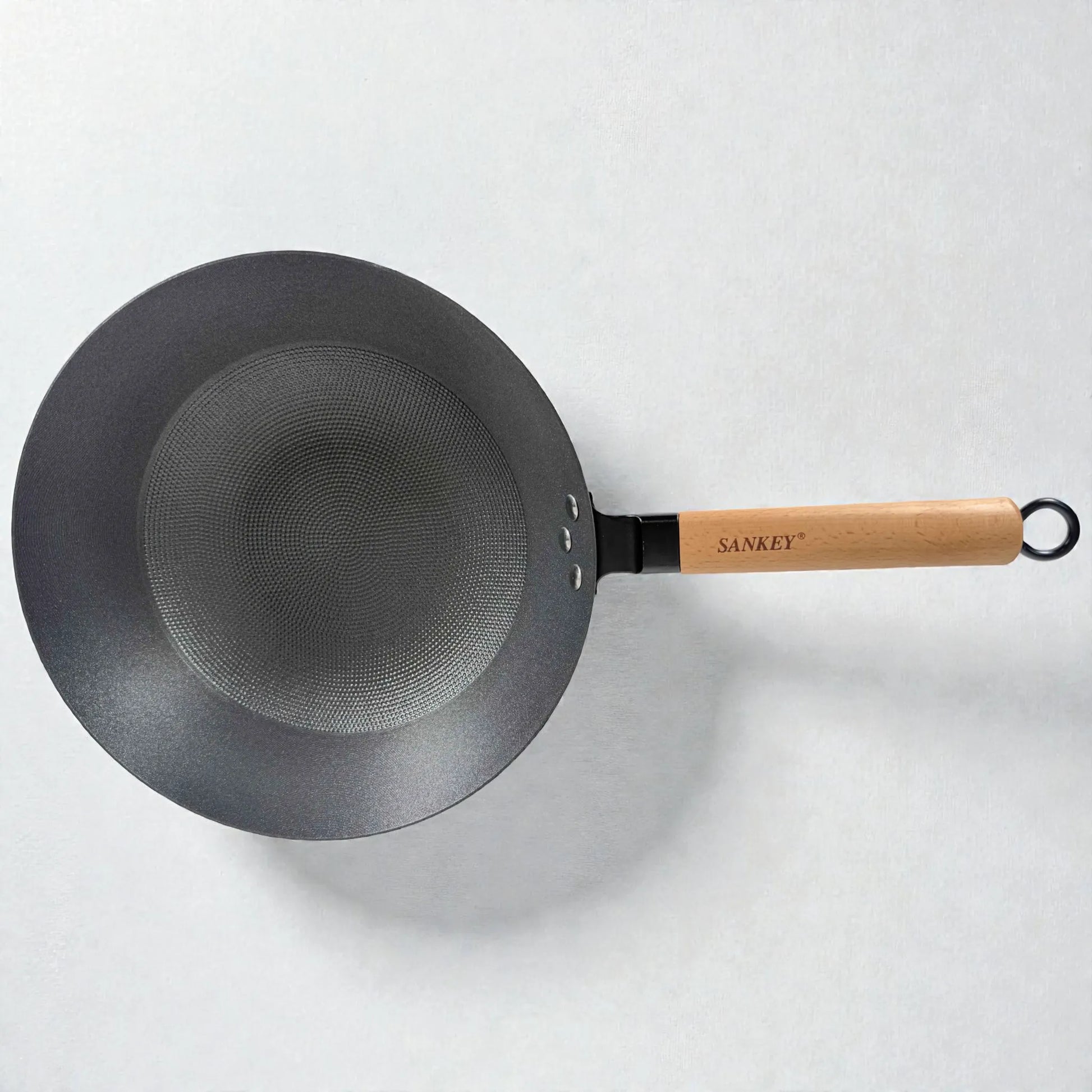 Vista superior del wok Sankey de hierro fundido negro 30 cm (12 pulgadas), interior con superficie tipo panal y mango de madera con logo, sobre fondo blanco.