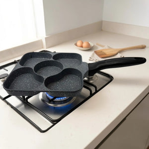 Sarten cuadrado Synamore 5 en 1 antiadherente en color gris moteado con mango negro, fotografiado en ángulo sobre una estufa de gas, mostrando sus cinco secciones de coccion separada.