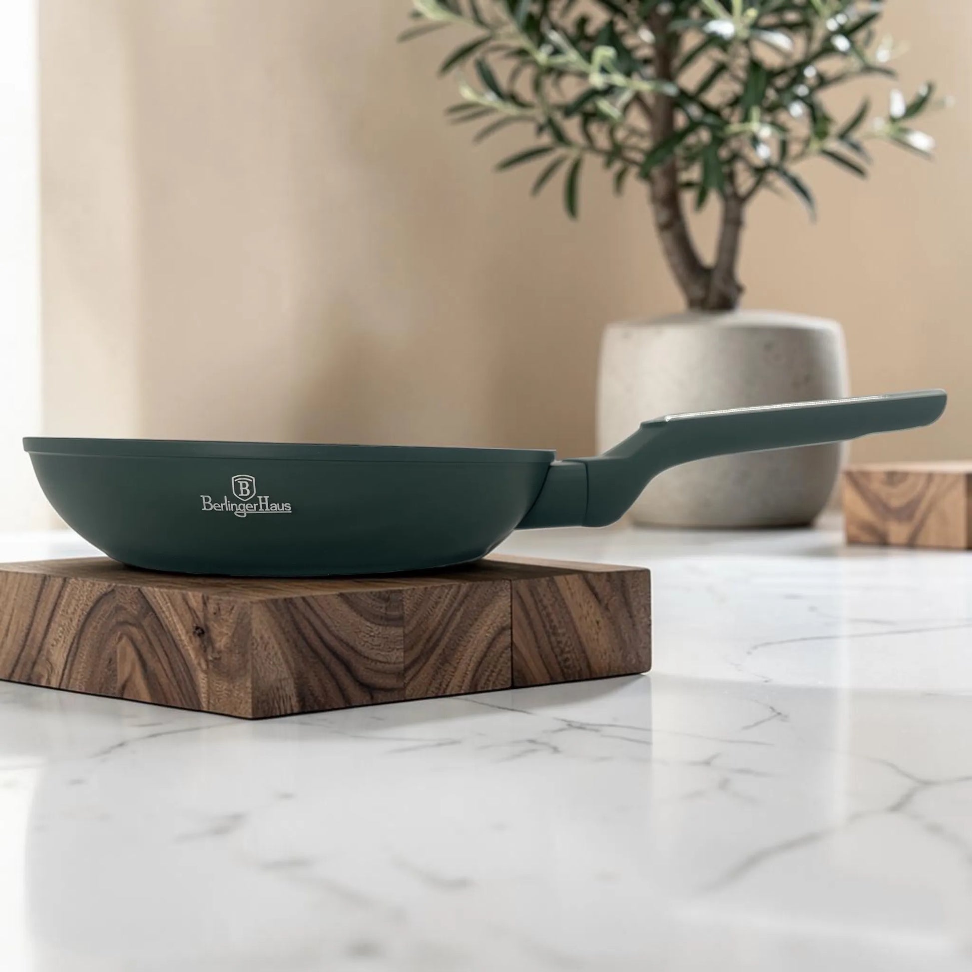 Sartén Berlinger Haus Matte Green antiadherente en color verde mate, vista lateral con mango ergonómico sobre base de madera.
