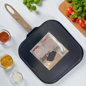 Sartén cuadrado de 28 cm marca Bergmann, color negro con mango de imitación madera, vista superior en cocina con ingredientes alrededor.