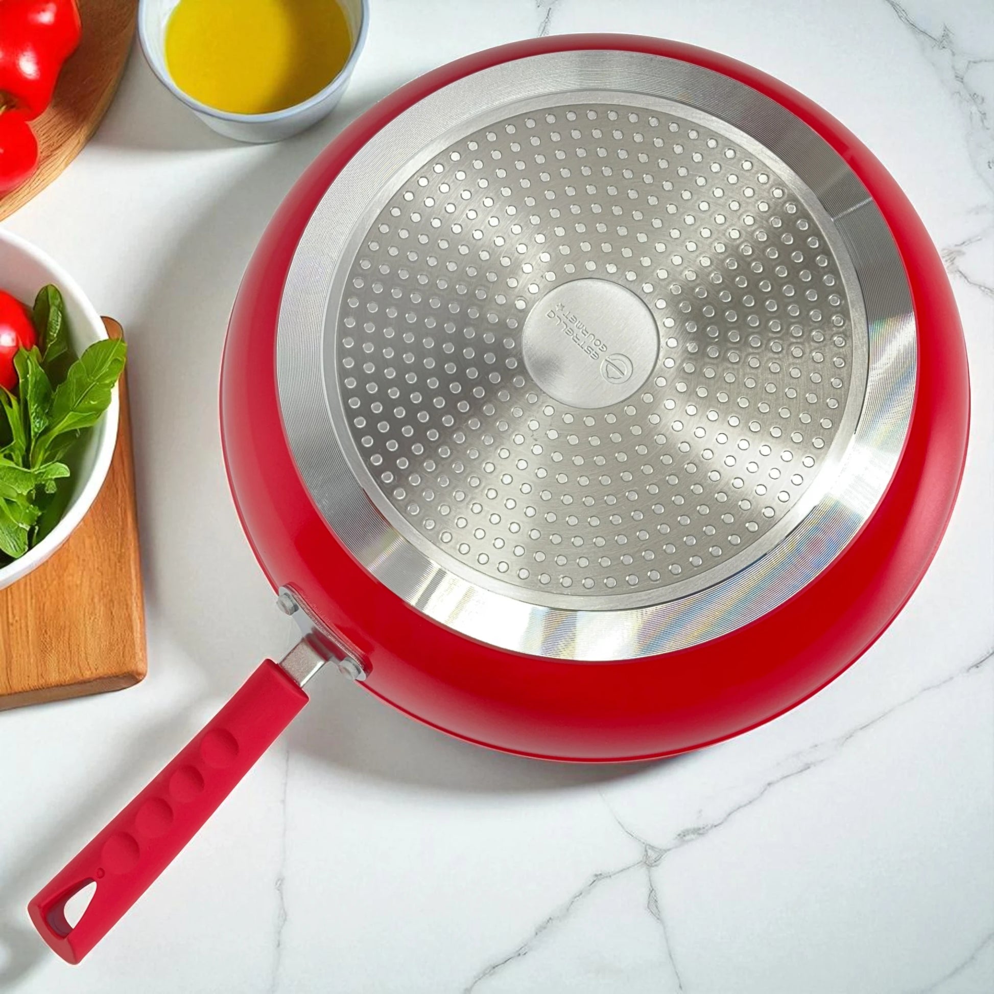 Detalle de la base difusora apta para inducción de un sartén Estrella Gourmet rojo 30 cm, vista inferior con disco de acero inoxidable.