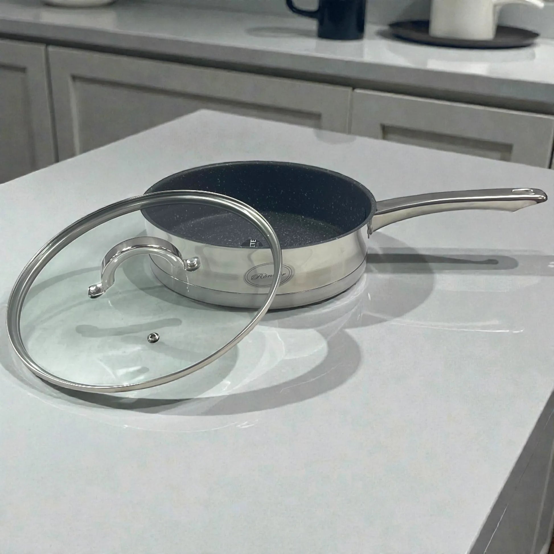 Sartén Rönner Austria con interior tipo granito y tapa de vidrio, cuerpo de acero inoxidable.