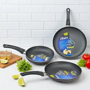 Set de 3 sartenes Oster antiadherentes color negro con efecto marmoleado, medidas 30.5, 24 y 20 cm, vista frontal en encimera de cocina.