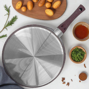 Base de sartén plano antiadherente Hotchef de 25 cm con recubrimiento de mármol, apto para inducción, rodeado de papas y hierbas frescas.