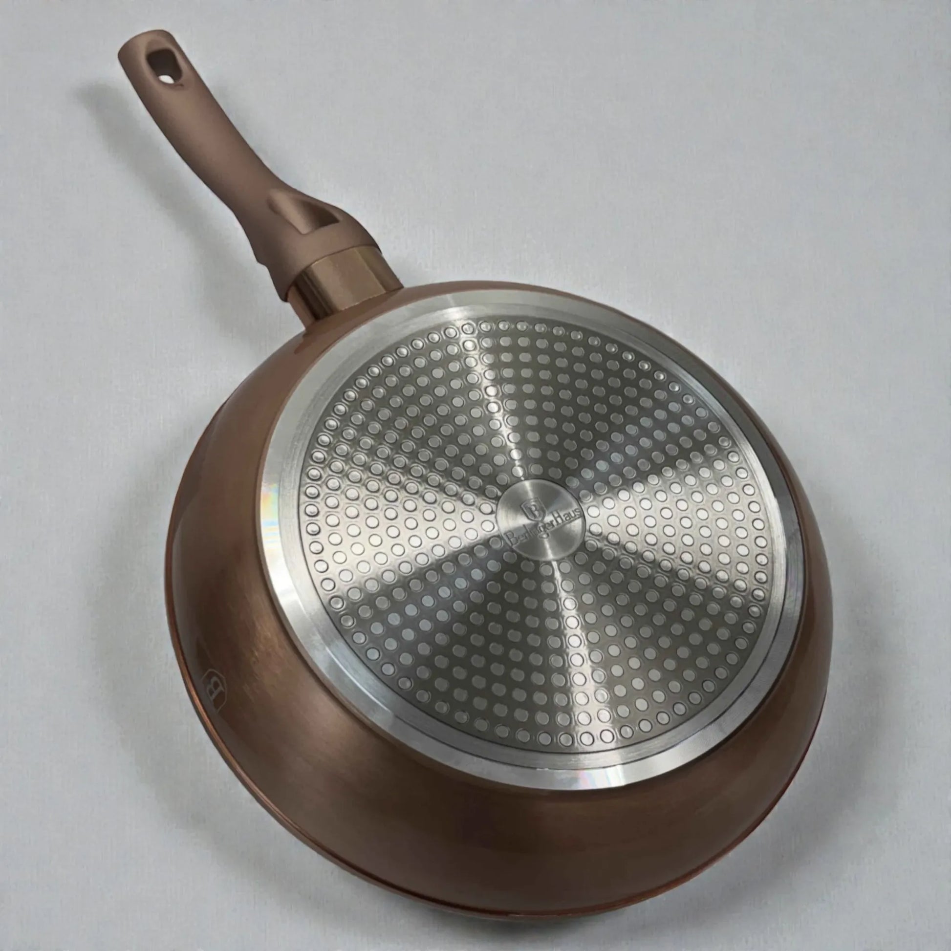 Vista inferior de sartén profunda Berlinger Haus Metallic Line Rosegold BH-1224N de 24 x 6.5 cm, con base metálica apta para inducción, cuerpo exterior rosegold y mango ergonómico en fondo blanco.