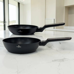 Sartén y sartén honda Berlinger Haus BH-8362 Black Rose Collection en color negro con mangos largos ergonómicos sobre encimera blanca.