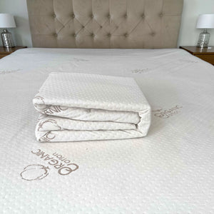 Protector de colchón Scarlett Classics Organic Cotton blanco, impermeable, mostrado doblado sobre el colchón para destacar material y acabado.