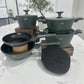 Set de cocina Berlinger Haus Matte Green con ollas, sartenes, tapas de vidrio templado y tapetes de silicona sobre encimera de mármol.