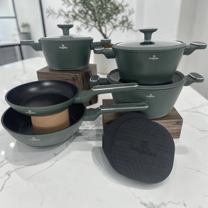 Set de cocina Berlinger Haus Matte Green con ollas, sartenes, tapas de vidrio templado y tapetes de silicona sobre encimera de mármol.