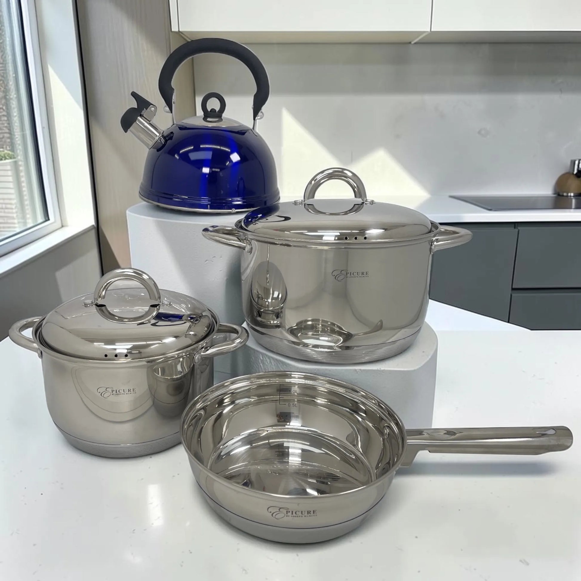 Set de cocina Epicure 7 piezas en acero inoxidable con sartén de 1 litro, ollas de 3 y 5 litros con tapa y tetera azul de 3 litros.
