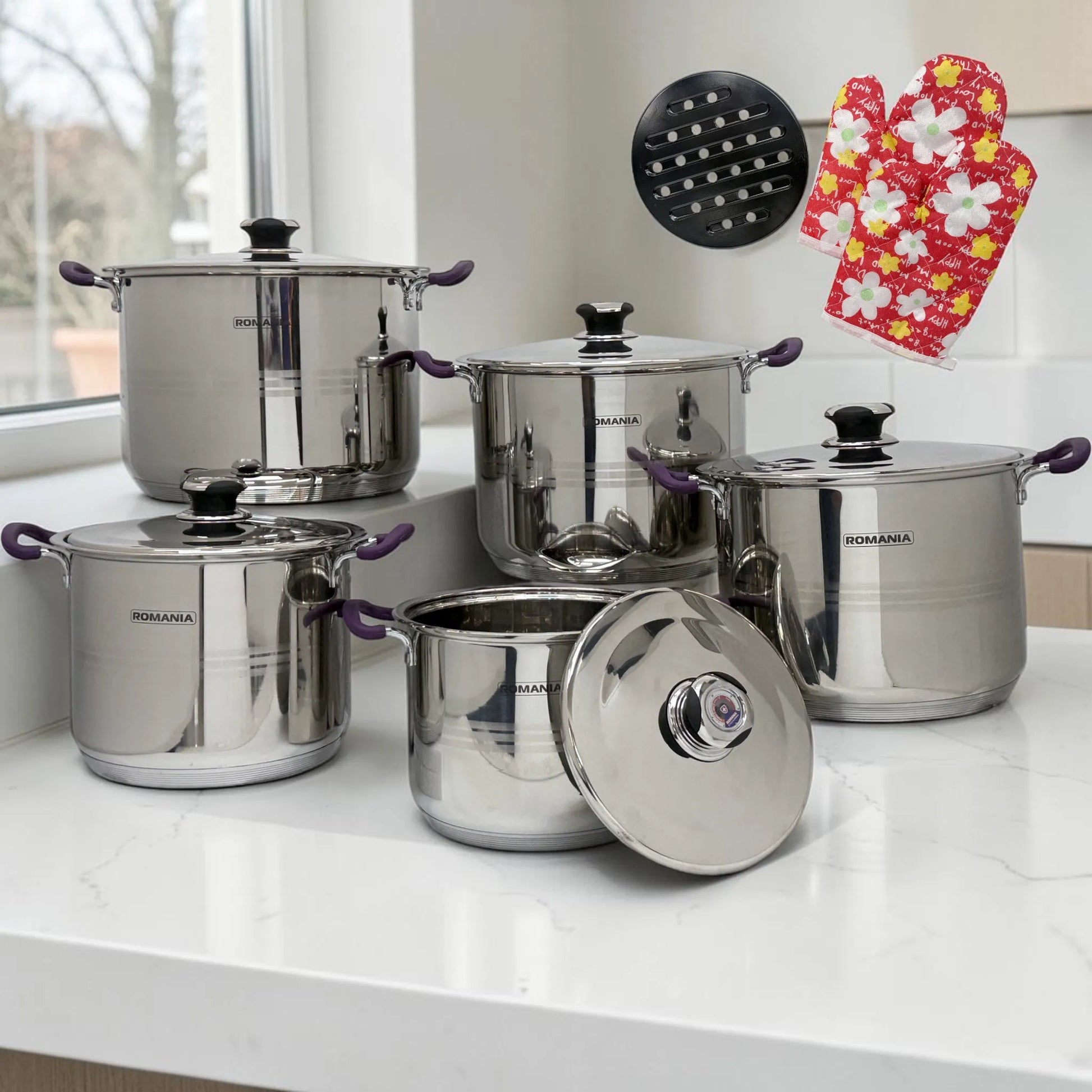 Vista general del set de ollas Romania Estilo Alemania de 10 piezas en acero inoxidable con mangos púrpura, acompañado de guante térmico y base metálica.