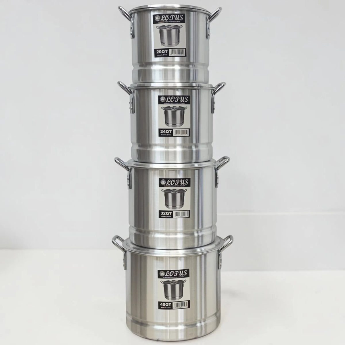 Ollas vaporeras de aluminio Lotus apiladas en tamaños 20QT, 24QT, 32QT y 40QT, equivalentes a 19, 23, 30 y 38 litros.