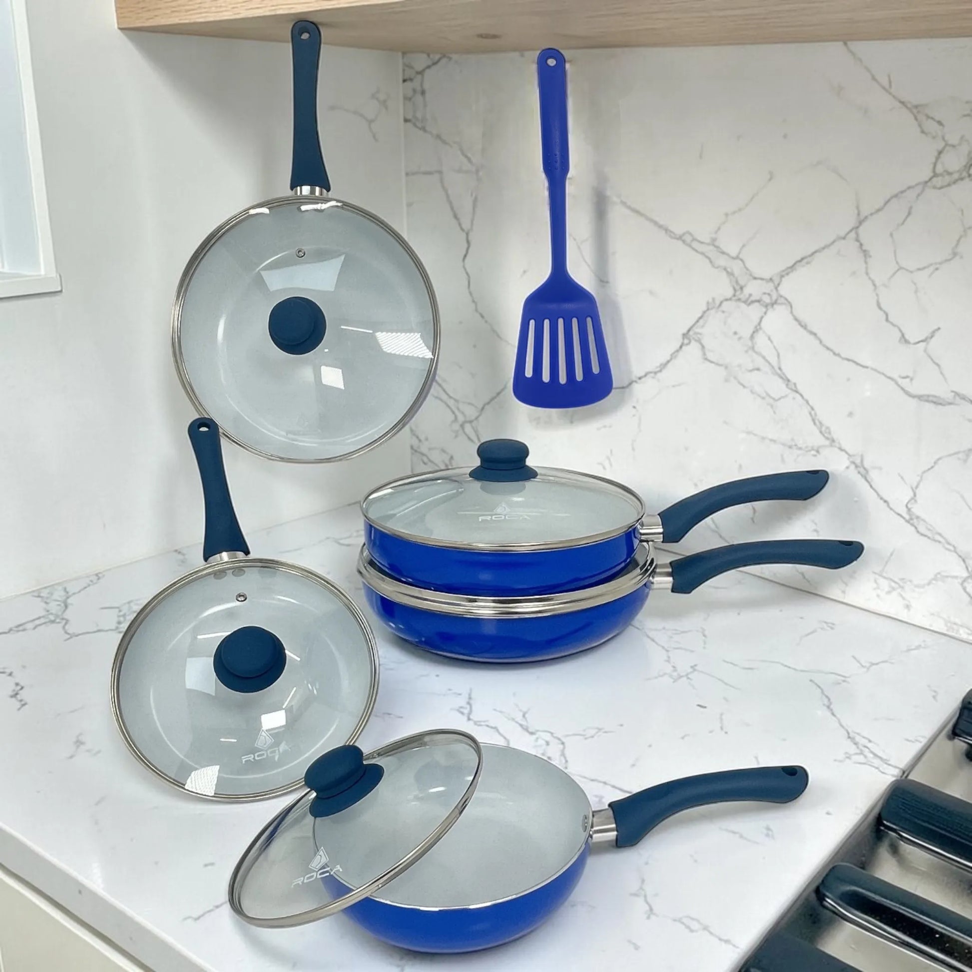 Set de sartenes ROCA color azul apilados con tapas de vidrio, mangos azul oscuro y espátula incluida, modelo KFS5000A.