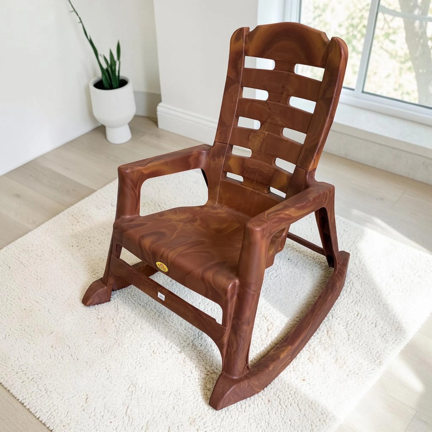 Silla mecedora plástica National acabado Mango, vista frontal lateral, con brazos, respaldo alto y diseño tipo madera.