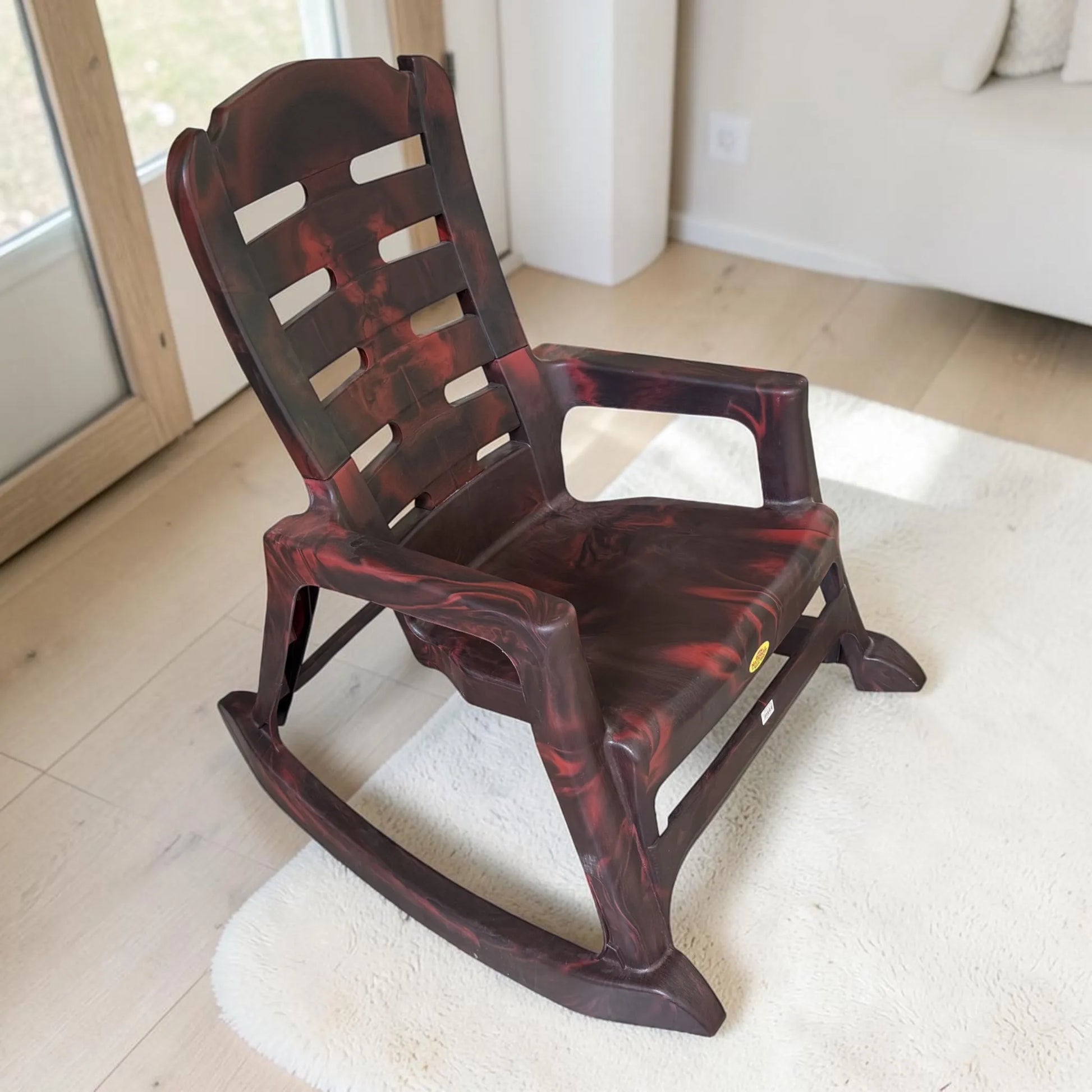Silla mecedora plástica National acabado Palo de Rosa en vista superior lateral, mostrando asiento amplio, brazos, respaldo ventilado y base curva.