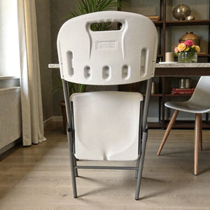 Silla plegable Lotus blanca vista posterior en posición plegada, mostrando logo Lotus en el respaldo, estructura metálica gris oscuro, ideal para ahorrar espacio.