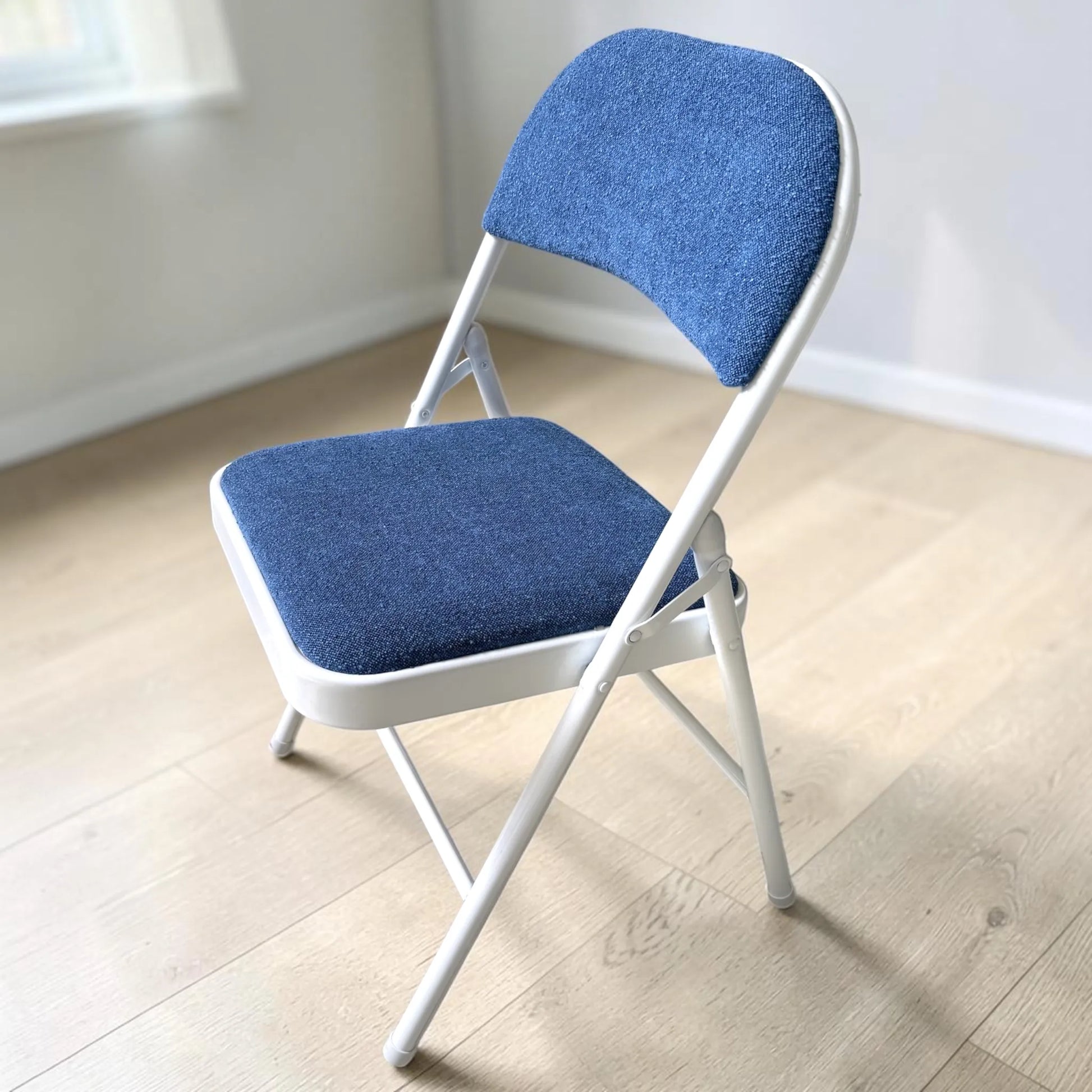 Silla plegable tapizada azul con estructura blanca, modelo CH-3023-BLU, vista lateral en ángulo.