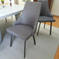 Par de sillas de comedor gris oscuro del set Ambienta DT-06-2237 junto a mesa rectangular 156×86×76 cm con cubierta tipo mármol blanco; ambiente moderno con piso de madera.
