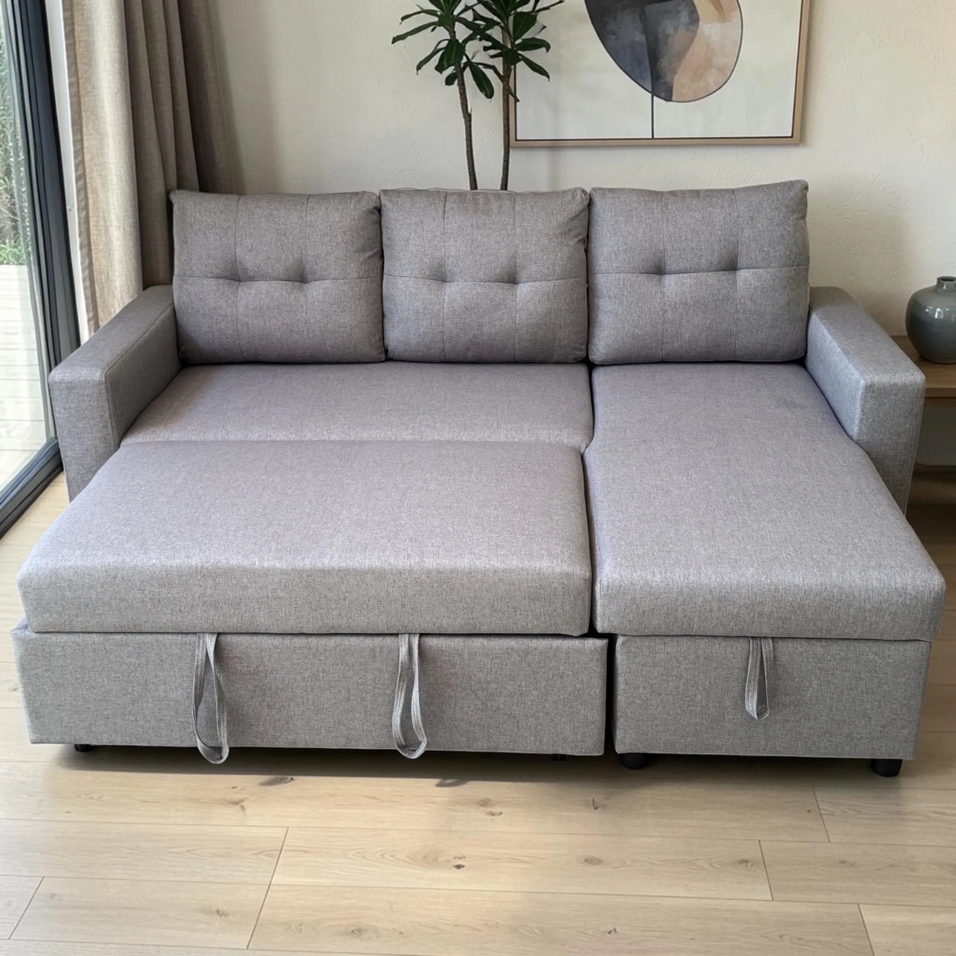 Sofá cama 2 en 1 Ambienta Home Decor color gris claro completamente extendido en modo cama, con chaise derecha, respaldos acolchados y tiradores frontales.