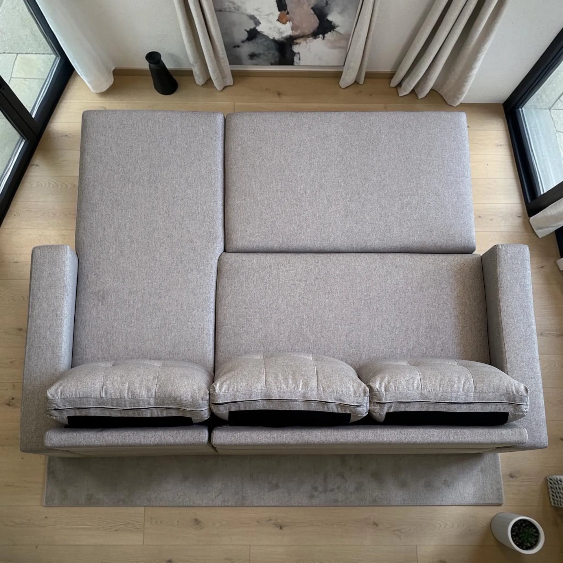 Vista aérea del sofá cama 2 en 1 Ambienta Home Decor completamente extendido en modo cama, superficie amplia, tres cojines removibles y diseño moderno color gris claro.