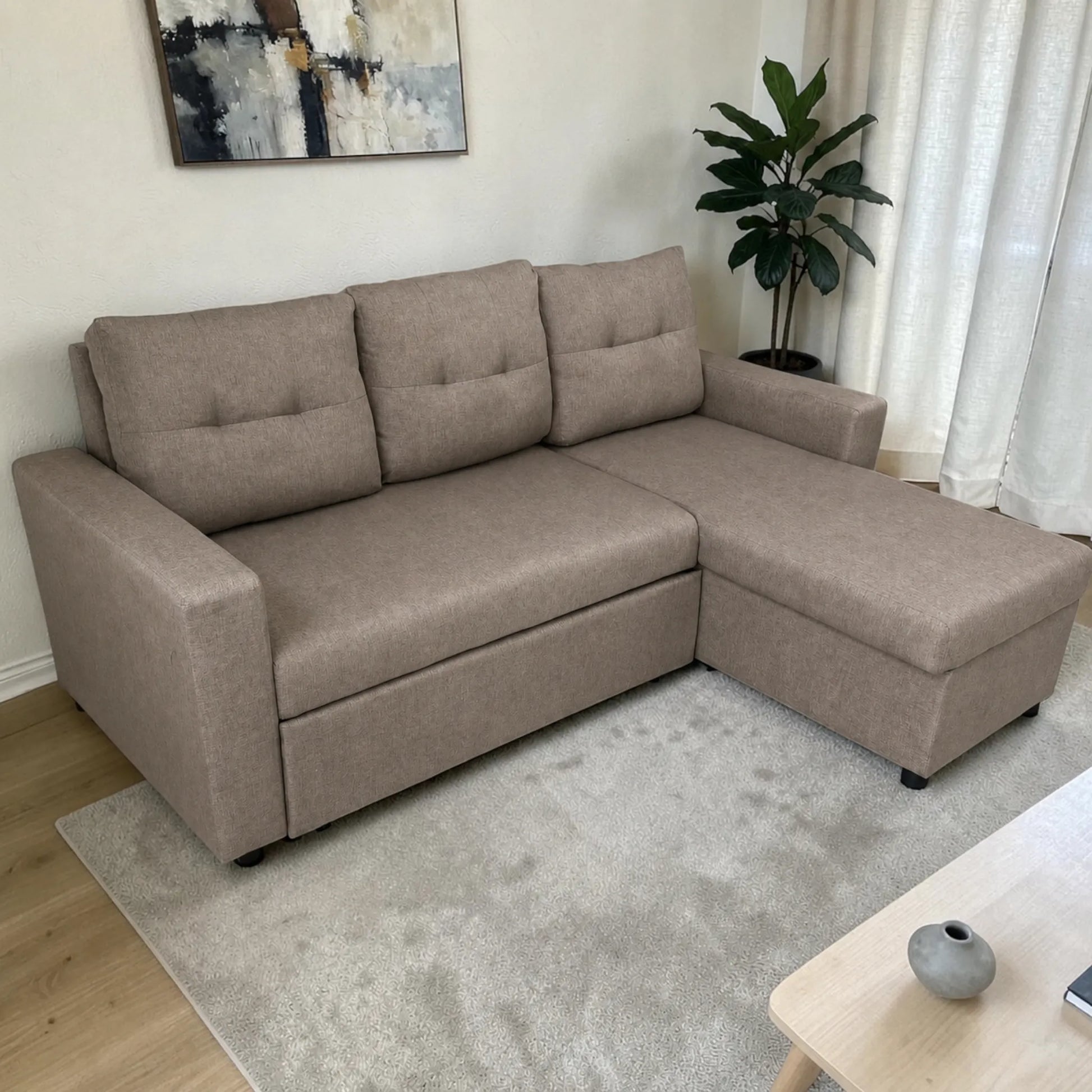 Sofá cama 2 en 1 Ambienta Home Decor color taupe con chaise derecha, vista lateral en sala moderna, tapizado tipo tela, brazos rectos y tres respaldos acolchados.