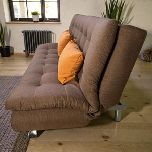 Vista lateral del sofá cama B8-2 color café de Ambienta Home Decor, mostrando grosor del asiento y respaldo capitonado, con 2 cojines decorativos mostaza/naranja.