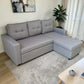 Sofá cama con cajón de almacenamiento Ambienta Home Decor color gris claro, vista lateral en sala moderna, diseño tipo chaise longue con brazos rectos y respaldos acolchados.