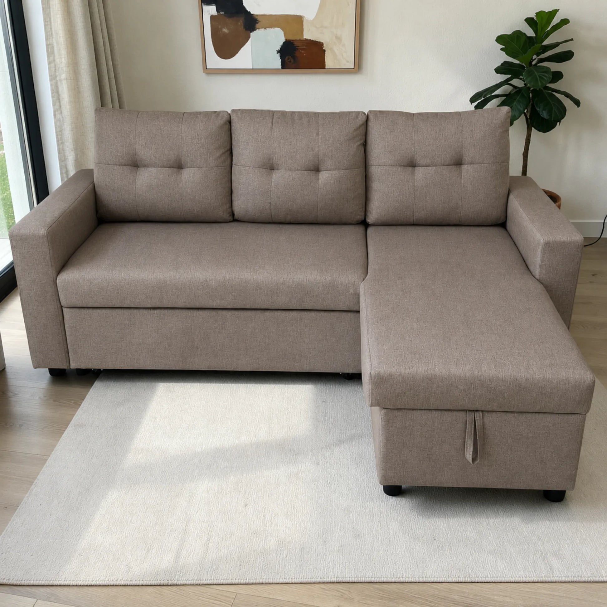 Sofá cama con cajón de almacenamiento color taupe, vista frontal con chaise derecha, tres cojines de respaldo capitonados, brazos rectos y patas negras.