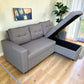 Sofá cama gris claro Ambienta Home Decor con cajón lateral abierto, vista diagonal, tapizado tipo tela, brazos rectos y compartimento de almacenamiento visible.
