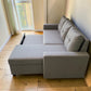 Vista lateral del sofá cama Ambienta Home Decor color gris claro con extensión abierta para convertirlo en cama, brazos rectos, respaldos acolchados y estructura deslizante.