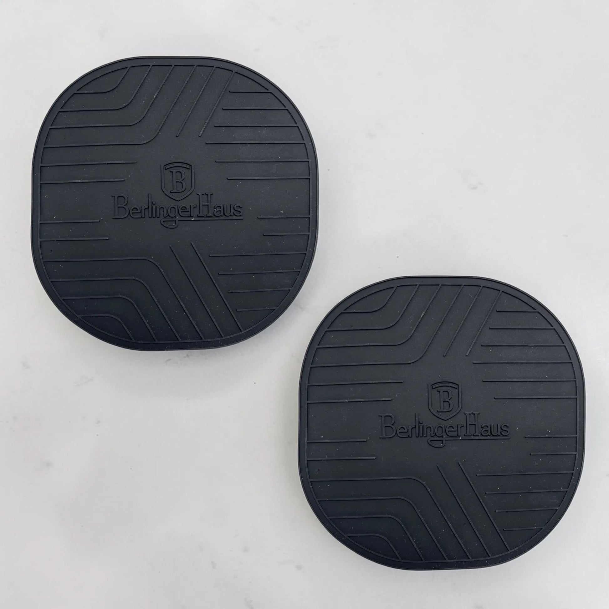 Par de tapetes de silicona Berlinger Haus incluidos en el juego de ollas Matte Green BH-8207NN, diseñados para proteger superficies del calor y apoyar ollas y cacerolas calientes.