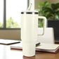 Termo blanco de acero inoxidable 1200 ml con asa y tapa de rosca con pajilla, colocado sobre escritorio junto a cuaderno.