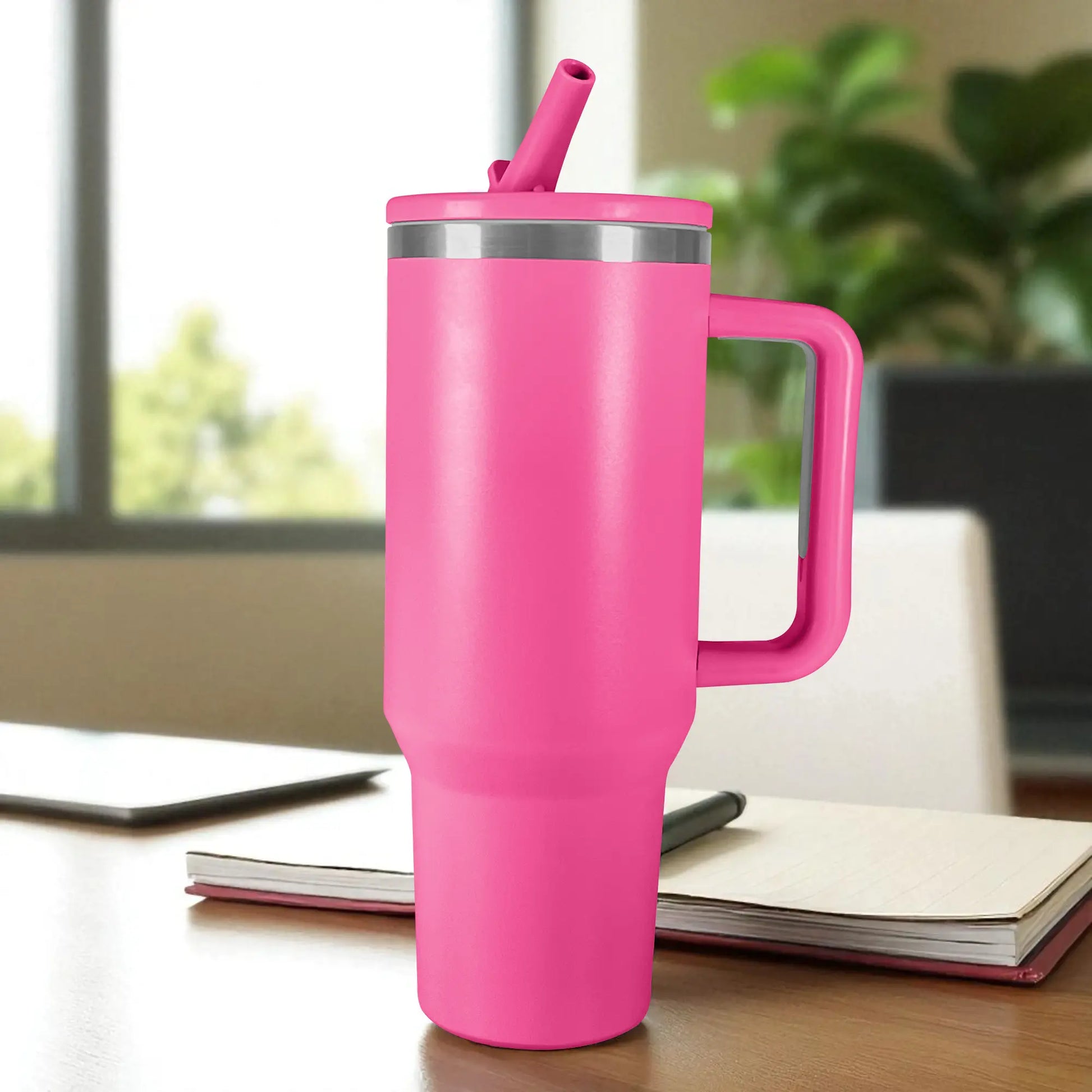 Termo rosa de acero inoxidable 1200 ml con asa y tapa de rosca con pajilla, colocado sobre escritorio junto a cuaderno.