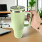 Termo de acero inoxidable color verde claro de 1200 ml con asa y tapa de rosca, sostenido en la mano en oficina.