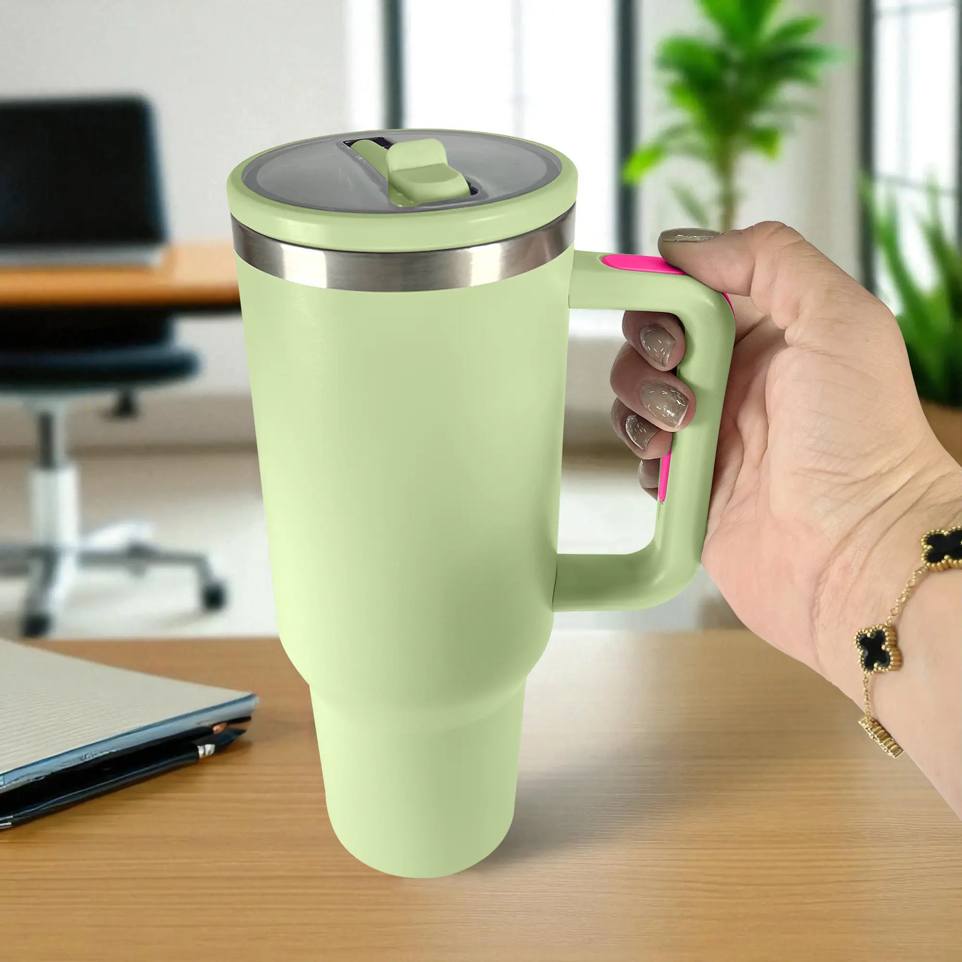 Termo de acero inoxidable color verde claro de 1200 ml con asa y tapa de rosca, sostenido en la mano en oficina.
