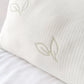 Primer plano de la tela blanca transpirable de una almohada de bambú Pacific Home, con textura perforada y bordado de hojas verdes.